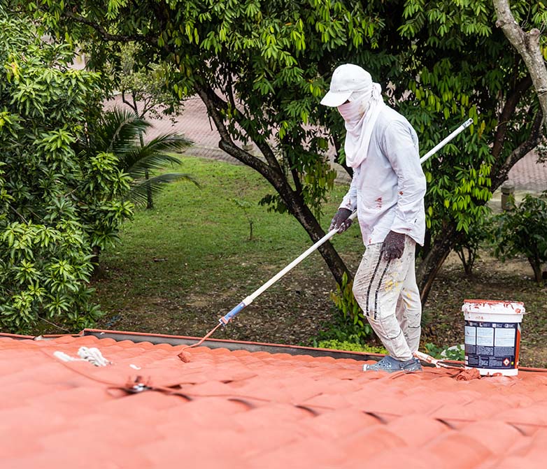 Worker painting a rooftop red